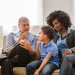 An article offering three tips to consider when navigating market volatility that shows a man and woman with their young child on the couch. The tips include: 1) Making a plan to ensure you have a diversified portfolio spread across stocks, bonds and cash, and then reviewing the plan at least once each year; 2) Focusing on the long term and not trying to predict the market or shifting your asset allocations; 3) Keeping up your contributions during periods of volatility to enable your retirement savings to grow over time. To learn more about saving for the future, contacting your local Mutual of America representative is encouraged.