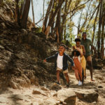 A young family running down a rocky mountain trail.