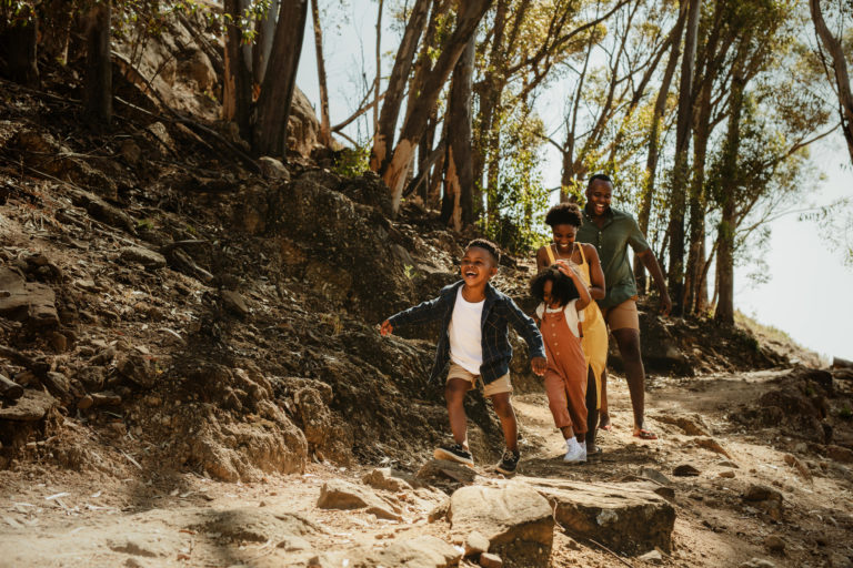 A young family running down a rocky mountain trail.