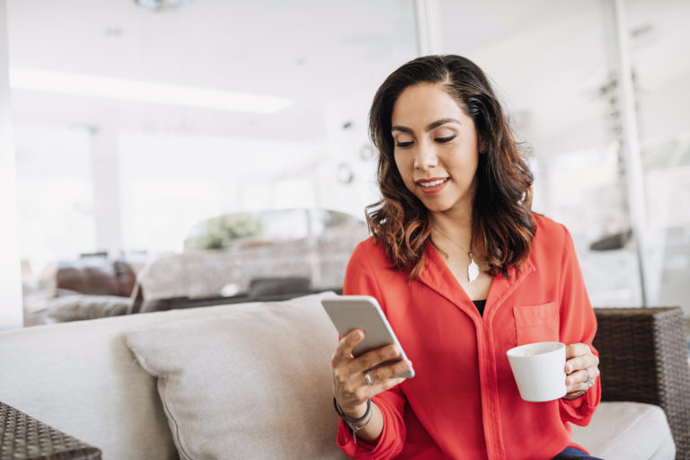 businesswoman sitting with coffee and browsing on smartphone