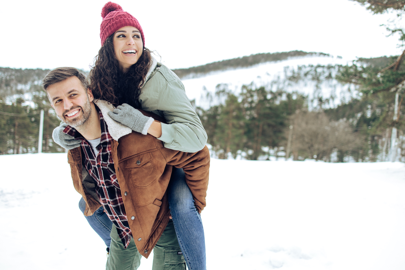 Man carrying his wife on shoulders and enjoying winter together